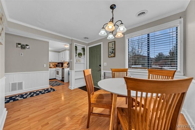 dining area featuring light wood-type flooring, visible vents, a notable chandelier, and ornamental molding