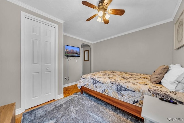 bedroom with arched walkways, ceiling fan, baseboards, and crown molding