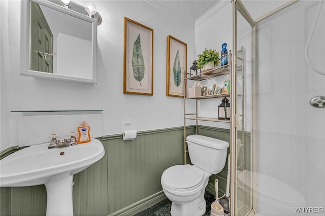 bathroom with a stall shower, wainscoting, crown molding, and toilet