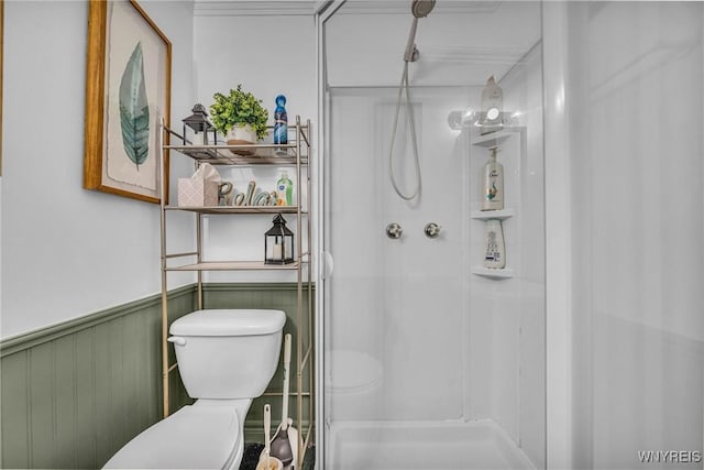 full bathroom featuring toilet, a stall shower, and wainscoting