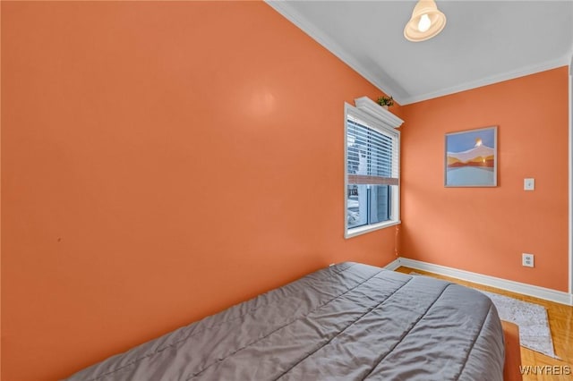 bedroom featuring baseboards, wood finished floors, and crown molding