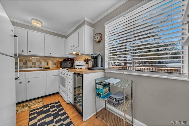 kitchen featuring beverage cooler, white appliances, a sink, light countertops, and crown molding