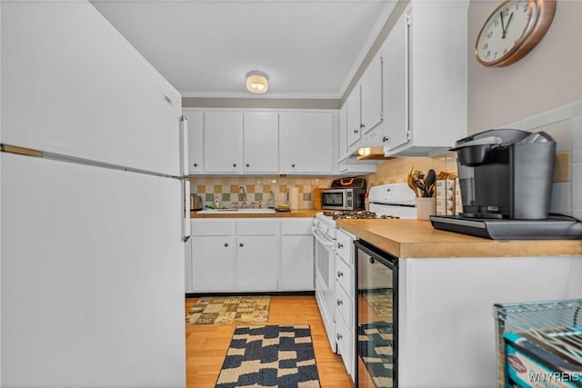 kitchen featuring white appliances, decorative backsplash, wine cooler, light countertops, and a sink