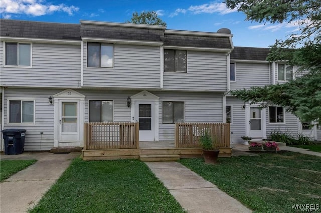 view of property featuring a front yard, roof with shingles, a wooden deck, and mansard roof