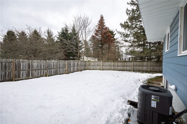 snowy yard with central AC and a fenced backyard