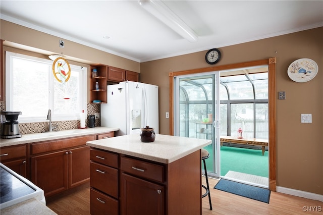 kitchen featuring light wood-type flooring, white refrigerator with ice dispenser, backsplash, and a sink