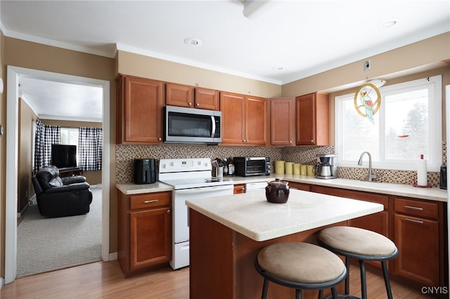 kitchen with white electric range oven, stainless steel microwave, light countertops, and a sink