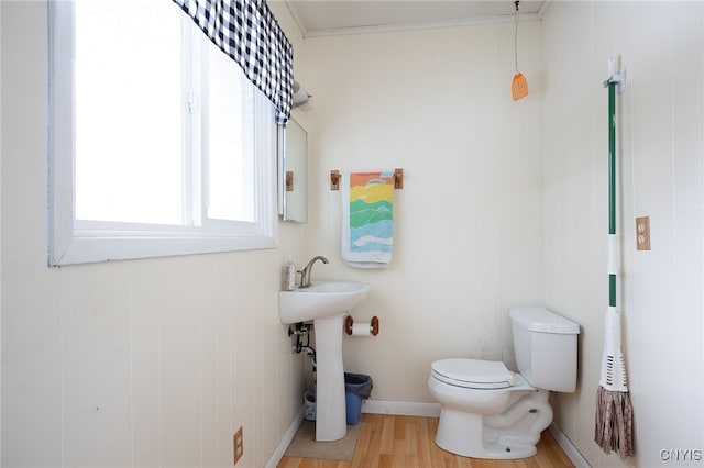 half bath featuring toilet, a sink, crown molding, and wood finished floors