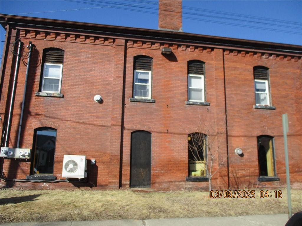 exterior space featuring ac unit, a chimney, and brick siding