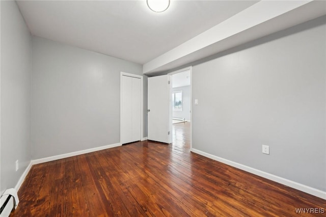 spare room with a baseboard heating unit, wood-type flooring, and baseboards