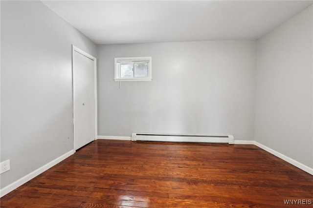 unfurnished room with baseboards, a baseboard heating unit, and wood finished floors