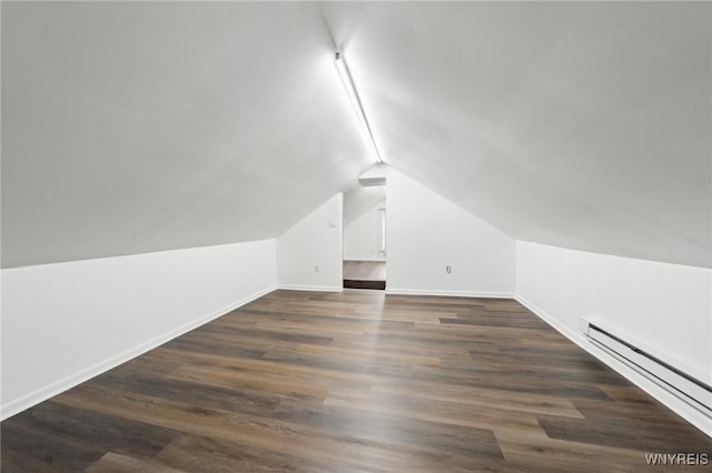 additional living space featuring dark wood-style floors, vaulted ceiling, a baseboard radiator, and baseboards