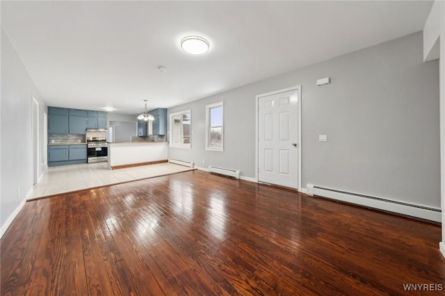 unfurnished living room with a chandelier, baseboard heating, and light wood-type flooring