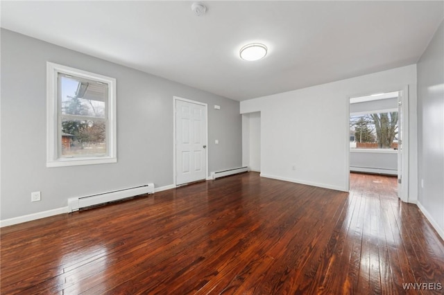 spare room with baseboards, a baseboard heating unit, and dark wood-type flooring