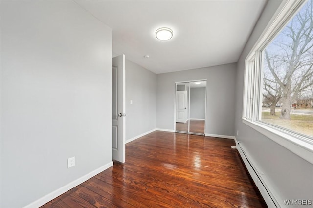 unfurnished bedroom featuring baseboards, baseboard heating, and wood finished floors