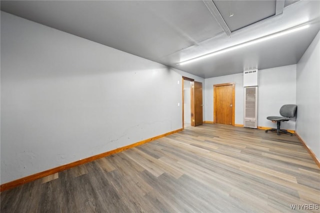 empty room featuring attic access, baseboards, and wood finished floors