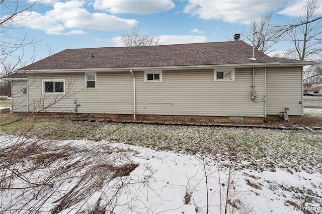 snow covered property with a shingled roof