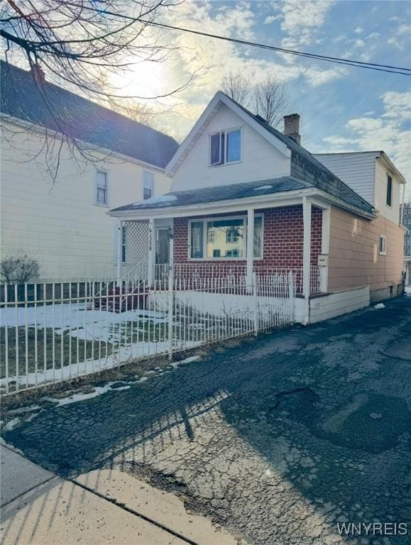 bungalow with a fenced front yard, brick siding, and a chimney