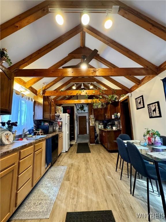 kitchen featuring dishwasher, dark countertops, light wood-style flooring, freestanding refrigerator, and a sink