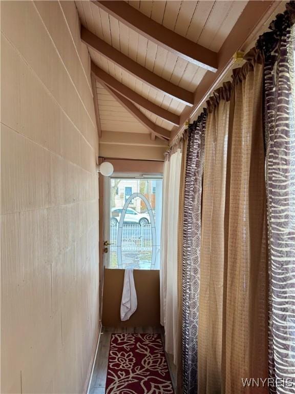 hall featuring vaulted ceiling with beams, wood ceiling, and wood finished floors