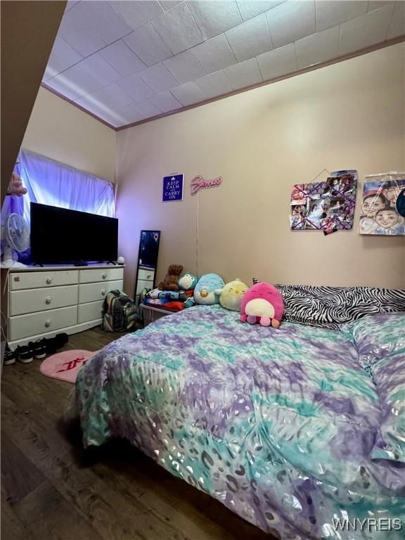 bedroom featuring ornamental molding and wood finished floors