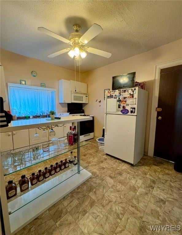 kitchen with a textured ceiling, ceiling fan, white appliances, and white cabinets