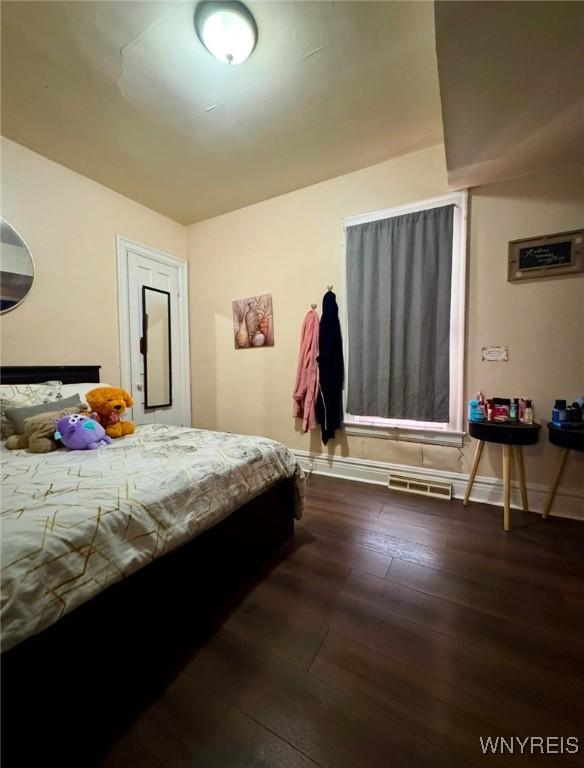 bedroom featuring visible vents, baseboards, and wood finished floors