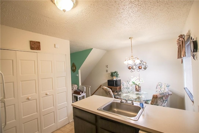 kitchen featuring hanging light fixtures, light countertops, a sink, and a textured ceiling