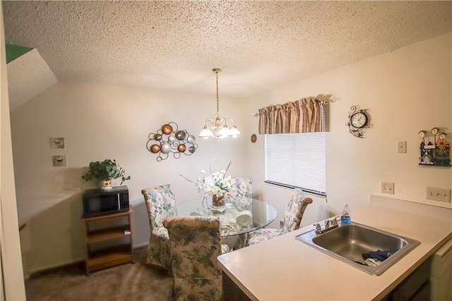 kitchen with hanging light fixtures, an inviting chandelier, carpet flooring, a sink, and a textured ceiling