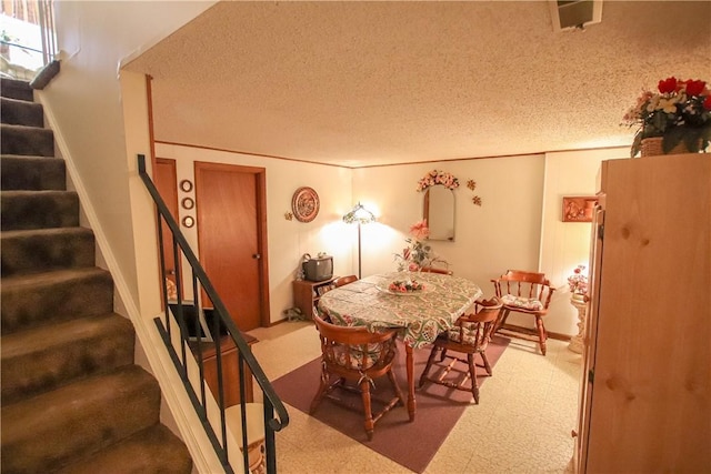 dining area featuring stairway, a textured ceiling, and tile patterned floors