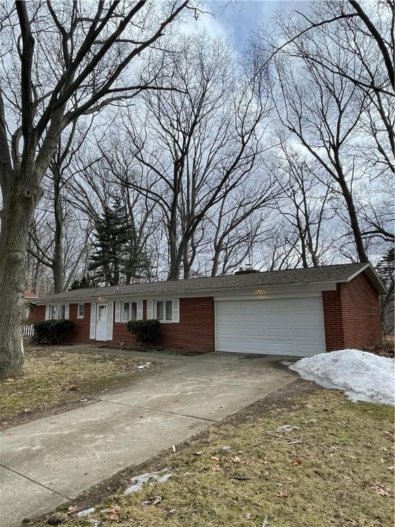 ranch-style home with driveway, brick siding, and an attached garage