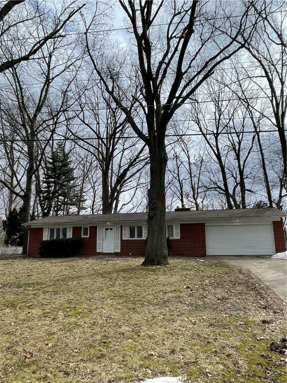 single story home with an attached garage, fence, concrete driveway, and a front yard