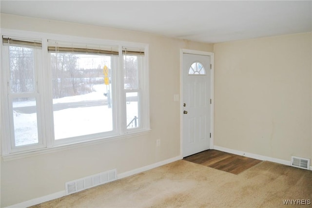 foyer entrance with carpet flooring, visible vents, and baseboards