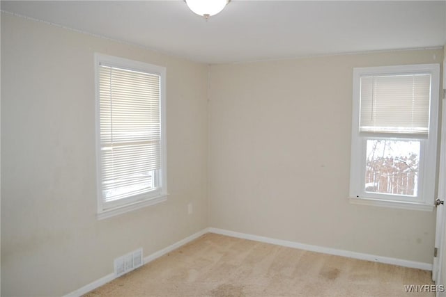 spare room with light carpet, a healthy amount of sunlight, baseboards, and visible vents