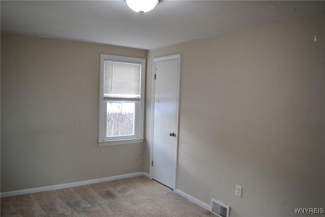 unfurnished room featuring light colored carpet, visible vents, and baseboards