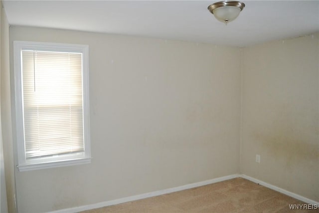 empty room featuring light colored carpet and baseboards