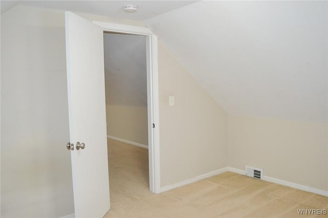 additional living space featuring light carpet, visible vents, baseboards, and lofted ceiling