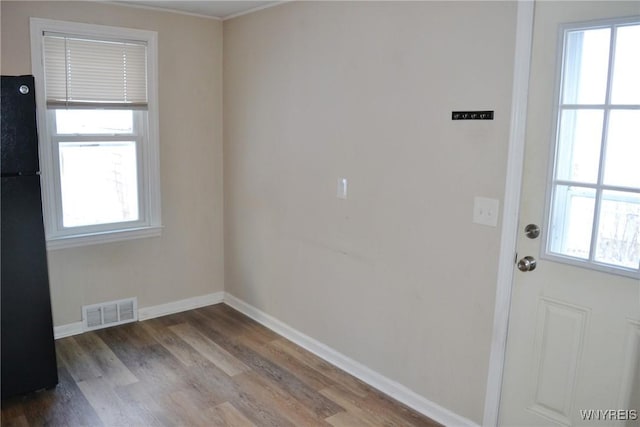 doorway to outside featuring baseboards, wood finished floors, visible vents, and a healthy amount of sunlight