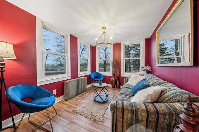 sitting room with an inviting chandelier, baseboards, radiator heating unit, and wood finished floors