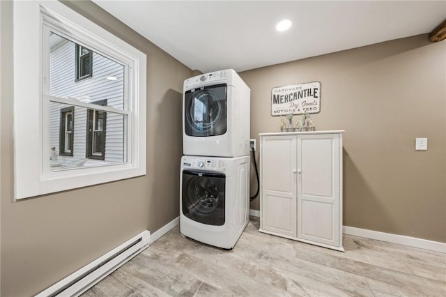 laundry room featuring cabinet space, baseboards, a baseboard heating unit, and stacked washer / dryer