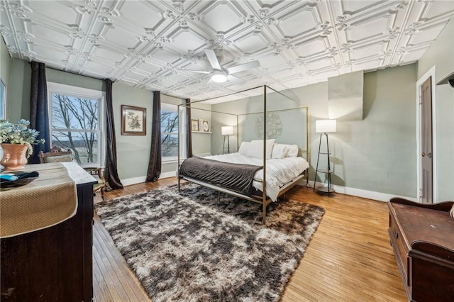 bedroom featuring an ornate ceiling, light wood finished floors, and baseboards