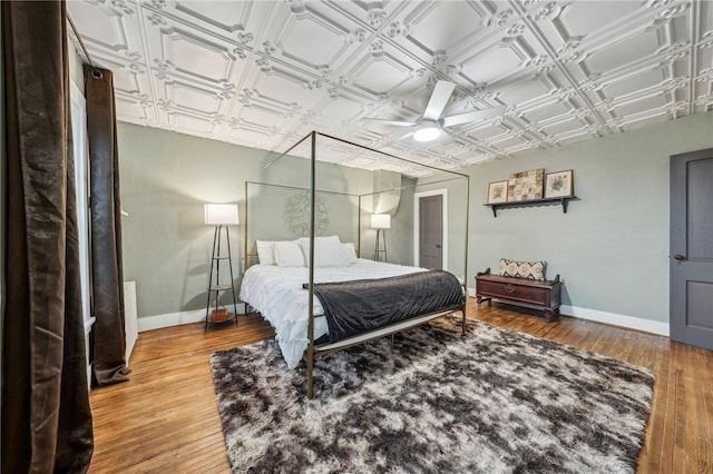 bedroom featuring light wood-type flooring, an ornate ceiling, and baseboards