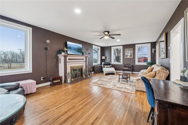 living area with ceiling fan, recessed lighting, a fireplace with flush hearth, baseboards, and light wood-type flooring