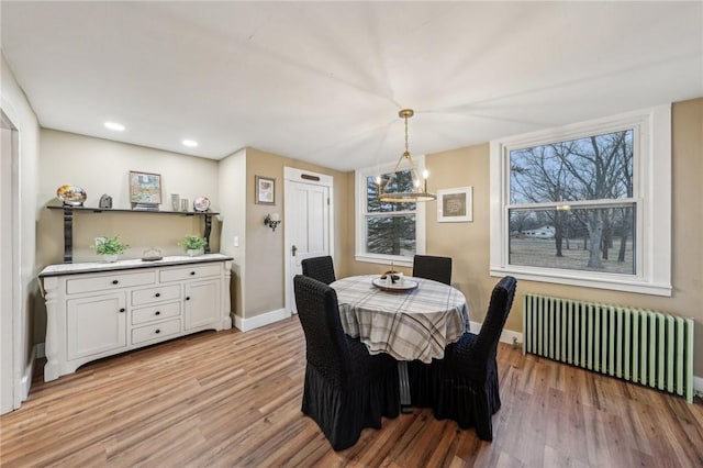 dining space featuring radiator heating unit, light wood-type flooring, and baseboards