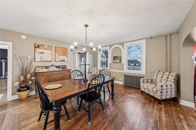 dining space with arched walkways, radiator, wood-type flooring, a chandelier, and baseboards