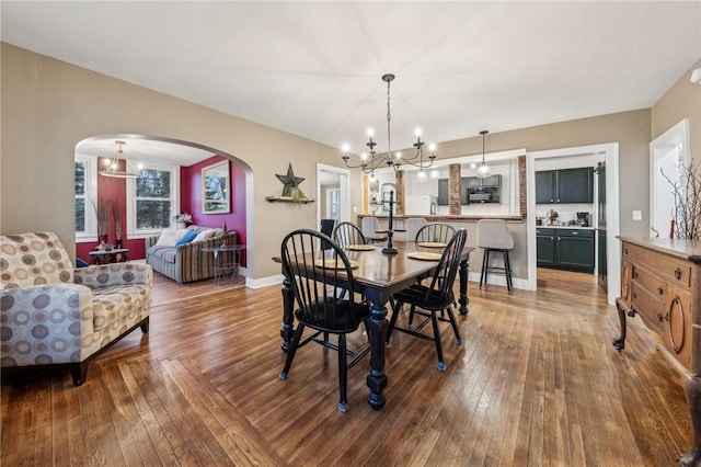 dining room with arched walkways, wood-type flooring, a chandelier, and baseboards