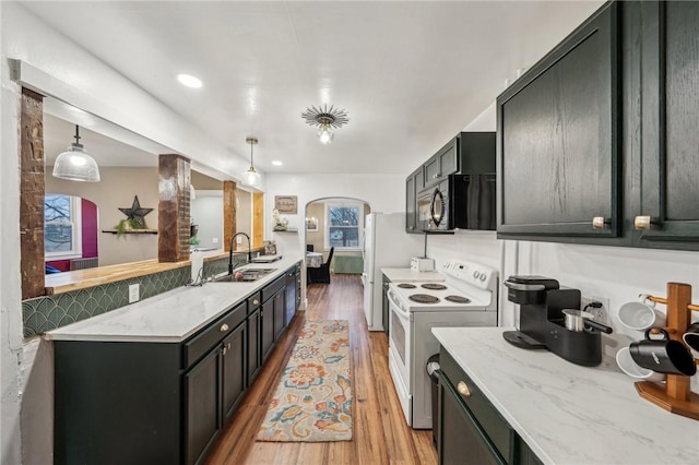 kitchen with black microwave, arched walkways, light wood-style flooring, a sink, and white range with electric stovetop