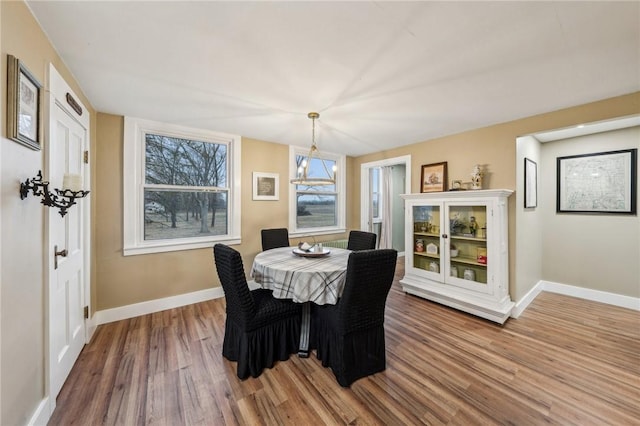 dining area featuring a chandelier, baseboards, and wood finished floors