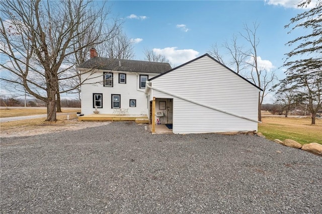 rear view of property featuring a chimney and a deck