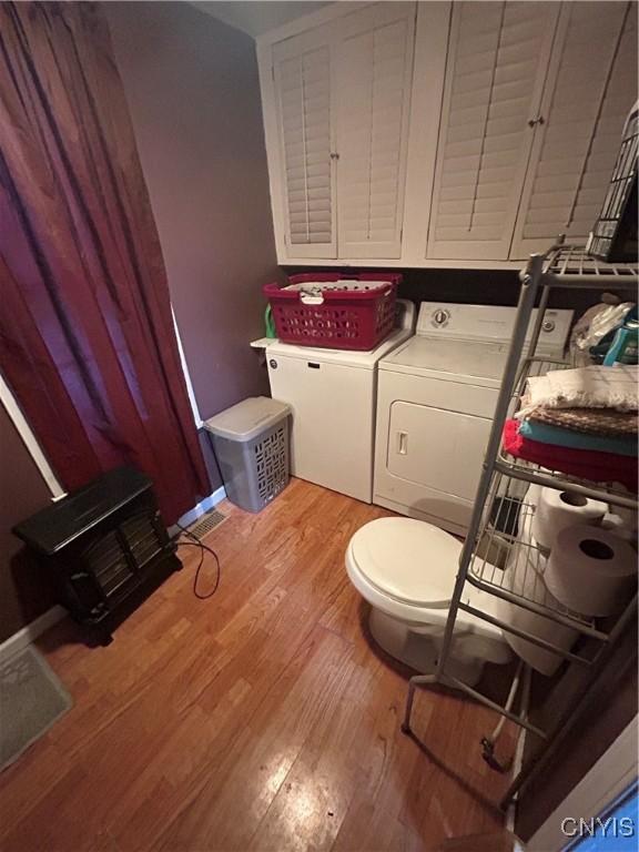 bathroom featuring independent washer and dryer, wood finished floors, and toilet